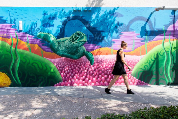 A woman passes mural art by Derek Donnelly who is known for his aquatic and coral scenes honoring his mentor BC Woo. 