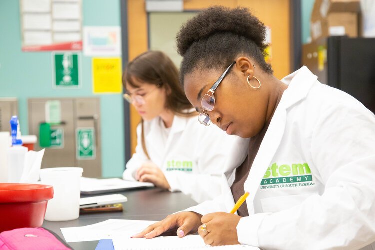 Caitlyn Coleman take notes during the STEM class where students learn about SEA-phages with hands-on lab work at USF.