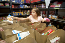 Lily Uline helps to assemble food bags at a food bank. - James Branaman
