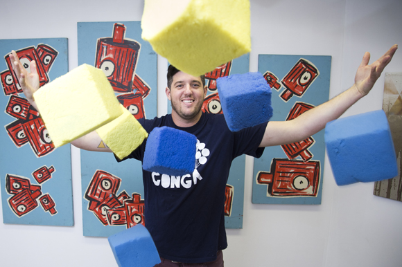 Ryan Swanson, Creator of Fun at Urban Conga has fun and poses amid a Wes Roos painting.   