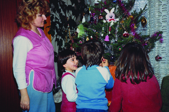 Karolak (the child at left) decorates a Christmas tree in Croatia with her cousins in 1987.