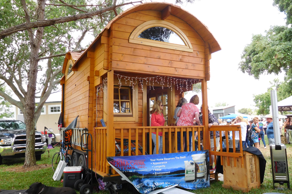 A tiny log cabin built by Unforgettable Tiny House displayed at the St. Pete Tiny Home Festival.