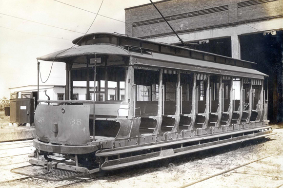 An open-sided streetcar from the early 1900's in front of the streetcar barn, which is now Armature Works.