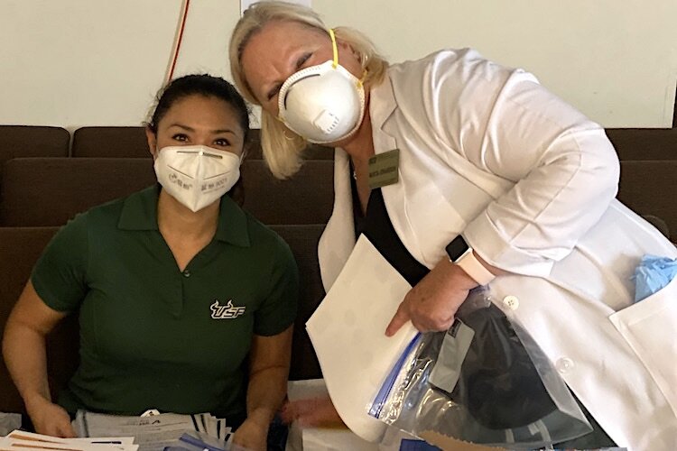 Ann Joyce and Marcia Johansson from the USF College of Nursing behind their COVID-19 PPE at the April 17 event supporting Sulphur Springs families at Abundant Life Church.