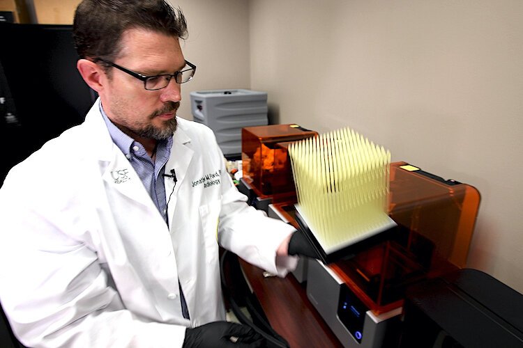 Dr. Jonathan Ford of USF Health examines a batch of newly printed 3D nasal swabs.