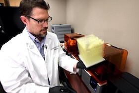 Dr. Jonathan Ford examines a new batch of 3D printed nasal swabs.