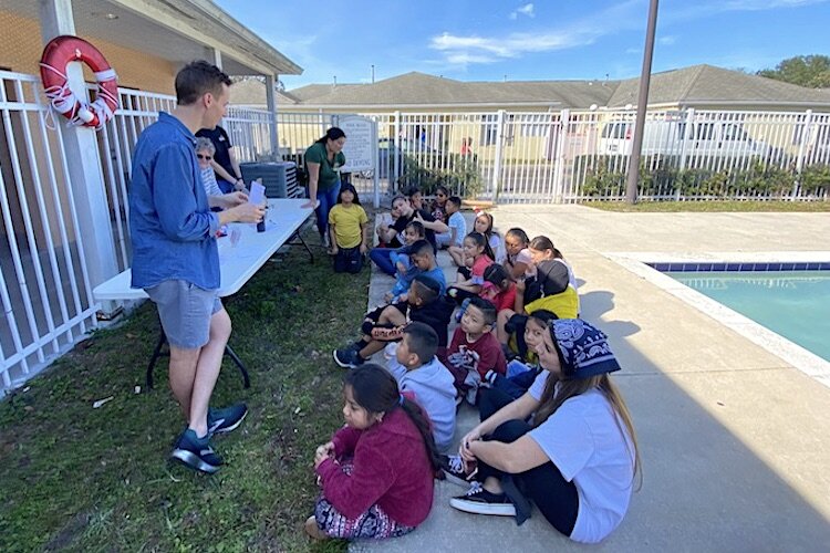 Logan Marx gives a talk, poolside, on a sunny December day at the Wholesome Winter Kids Camp at The Groves at Wimauma.