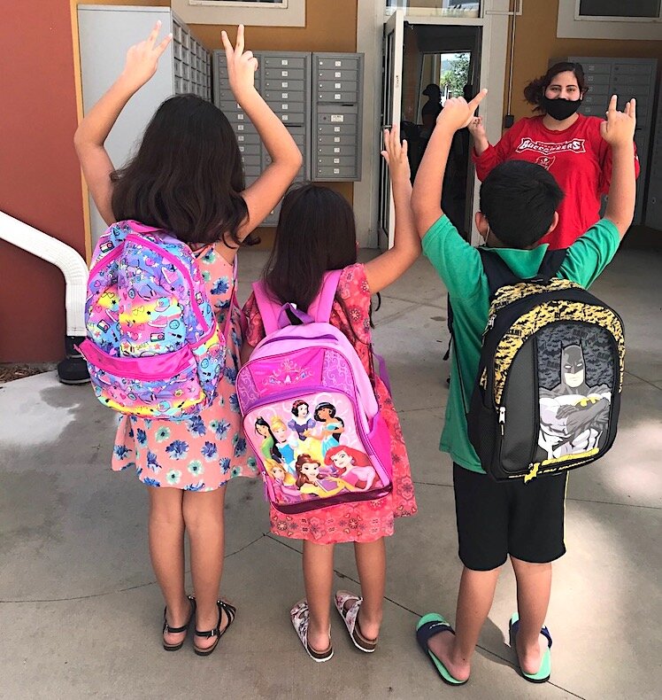 Children living public housing proudly wear new backpacks handed out before school started in September.