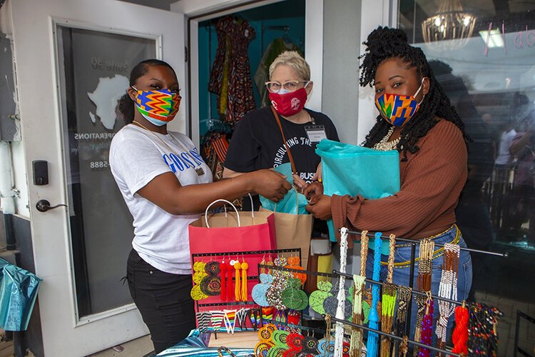 Anji Degante, right, proprietor of "Accent Styles Boutique" and part of the Black Business Bus Tour, assists shoppers on Saturday's stop.