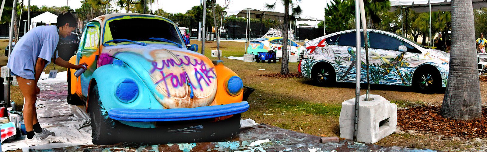 Local artist Emily Tan spray paints a customer’s car for the GFA Carmada Art Car Extravaganza during which several vehicles will be transformed into mobile works of art. 