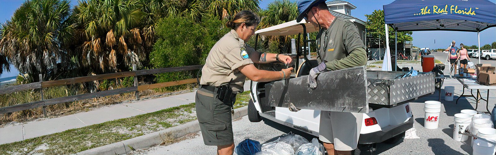 Park ranger and event coordinator Beth Reynolds attempts to weigh a six-foot-long, nail-studded plank that volunteer Randy discovered on the beach during International Coastal Cleanup Day.