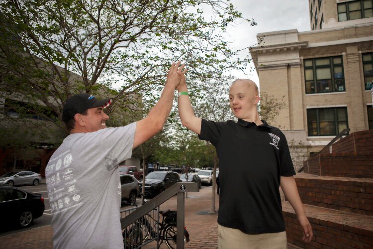Brock Odom high-fives William Spinks at the inaugural lighting of downtown Tampa's Old City Hall with blue and yellow lights to recognize and celebrate World Down Syndrome Day on March 21.