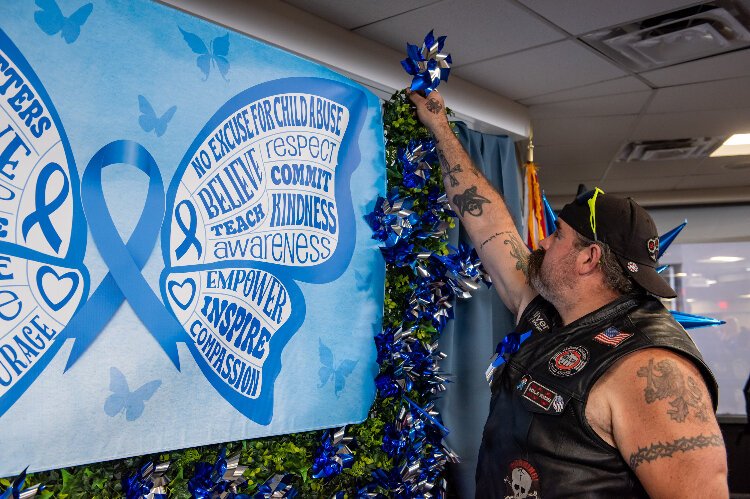 A member of the Bay Bridges chapter of Bikers Against Child Abuse adds to a pinwheel garden during an early April cemermony at Tampa General Hospital for Child Abuse Prevention Month. 
