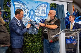 Mello, president of the Tampa Bay chapter of Bikers Against Child Abuse, presents Tampa General Hospital President and CEO John Couris with a tiny "cut," or biker's vest, during a ceremony for National Child Abuse Prevention Month.