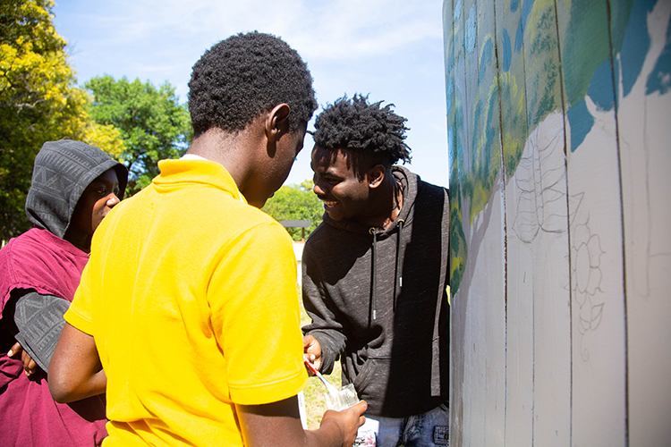 David Smith and his peers take turns painting at the Tampa Heights Community Garden.