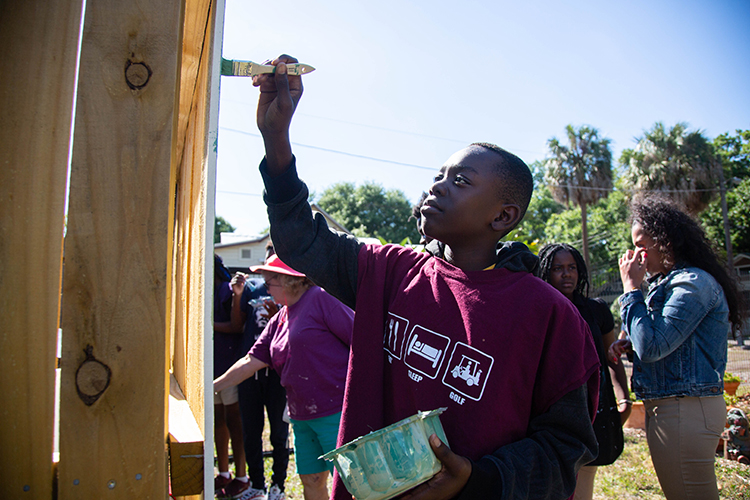 Jason Nelson helps paint a mural at the Tampa Heights Community Garden with the Tampa Heights Jr., Civic Association (THJCA) after-school program.