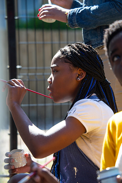 Jazmine Eubanks helps paint the welcome sign at the entrance of the Tampa Heights Community Garden.