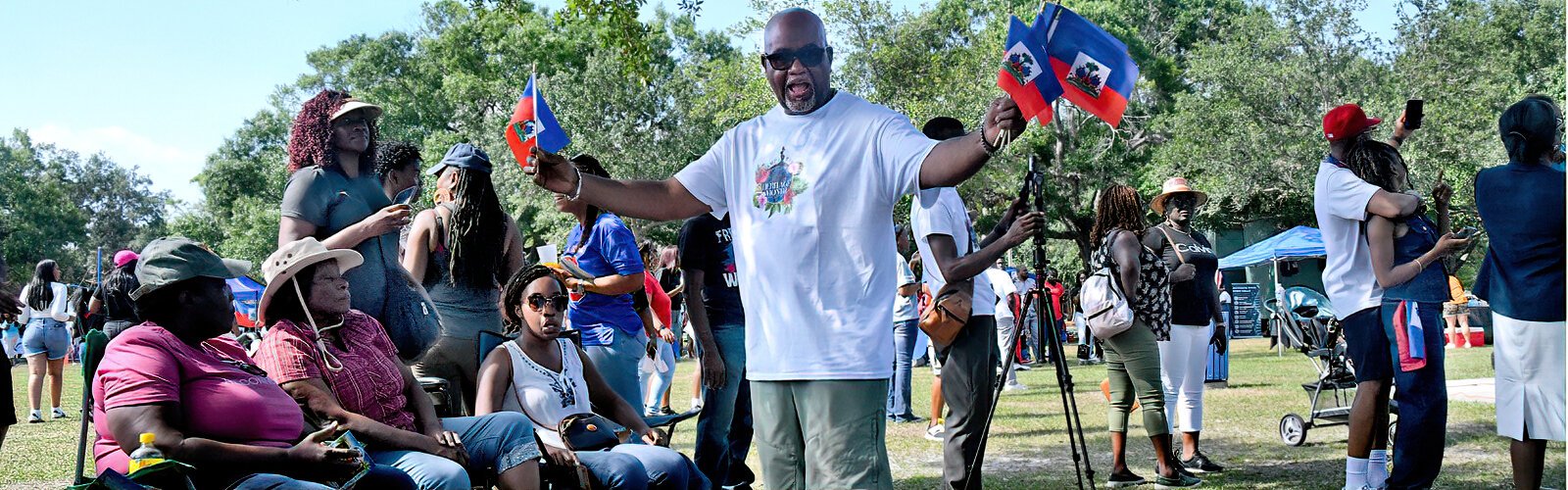 A proud Haitian attendee distributes small flags to honor Haitian Flag Day, which is celebrated in Haiti on May 18th.