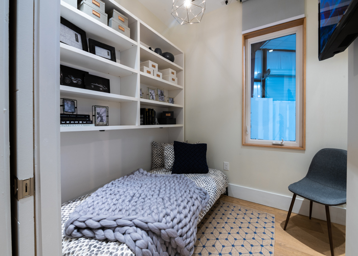 The guest Murphy bed folds up into the wall to create a desk space under the shelves.