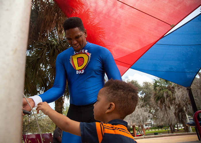 Maurice Vernon, aka Super Dad, plays with his son Dylan, age 2, at the Macfarlane Park where the 24M Dads 5K March will be held March 19th.