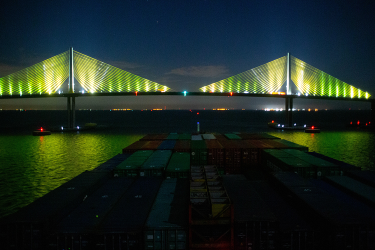 A Chinese container ship guided by Harbor Pilot Carolyn Kurtz glides under the Sunshine Skyway Bridge with a 30-foot clearance.