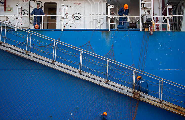 Crew members tie down the ship after docking.