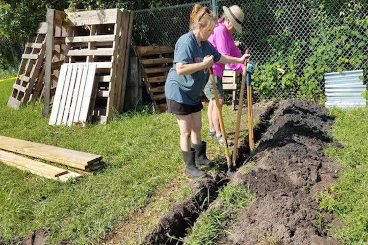 Volunteers dig a trench to secure a new fence at Walker Middle School.