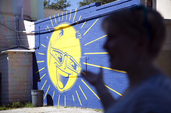 Audrey Henneman shows tour participants Chad Mize's Mr. Sun Mural (2014). 