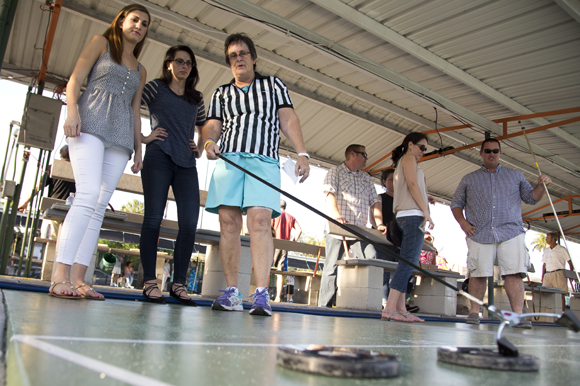 Bonnie Walker (R) teaches Kelly Clark and Megan Body the rules of shuffleboard at realize Bradenton's PopUps for a Purpose event. 