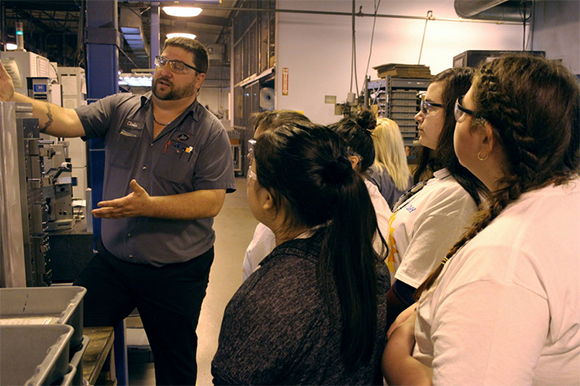 Chris Tatro, a CNC (computer numeric controlled) machinist at Southern Manufacturing Technologies, shows students from Marshall Middle School one of the pallets that go in one of SMT’s CNC Horizontal Mills.