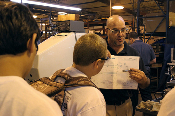 Joe Paciella, a supervisor at SMT, shows Marshall Middle School students how an item went from the drawing board to production.