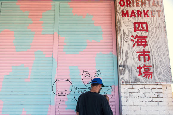 Cory Robinson adds color to wall space outside Cafe Hey and an Asian grocery store.