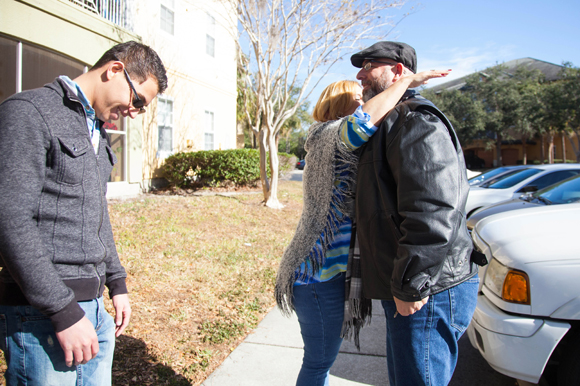 Kevin Estrada looks on as Diane Cortes hugs Marco Lopez, also a Puerto Rican refugee.