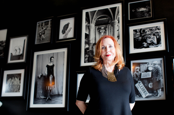 Carolyn Wilson, aka CW, stands in front of vintage photos at the entrance of CW's Gin Joint.