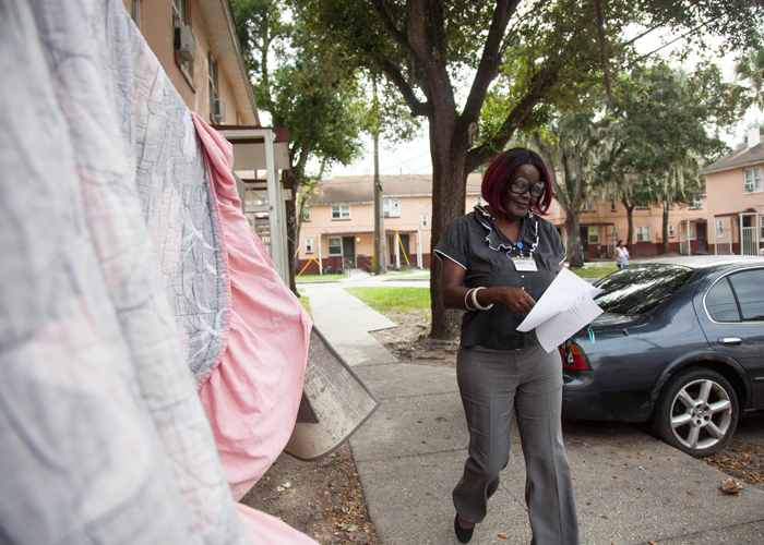 Reva Iman, a community coach and resident counsel, passes out fliers for a workshop aimed to help people find jobs, register to vote, and restore civil rights at Robles Park Village.