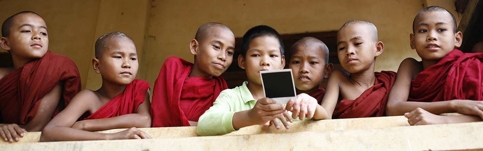 Monk novices look at a photograph taken by a student in Amber Sigman's co-led photo class in Myanmar.