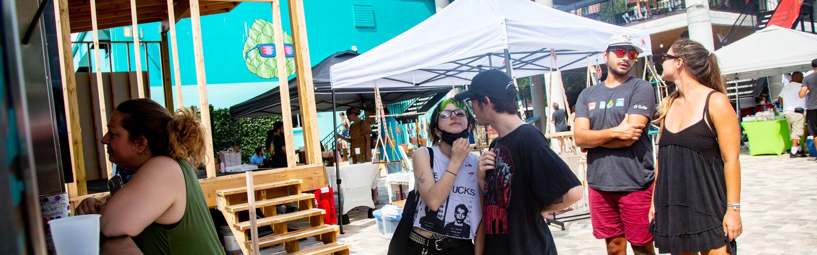 A couple kisses while waiting to place an order at All Good St. Pete Food Truck which offers vibrant textured sticky wraps, nachos, and ice cold juice spritzers for a hot day.