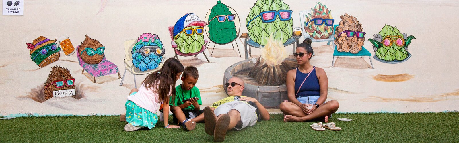 Seth and Jessica Milbrand of Palm Harbor relax with their two children in a shaded outdoor space at HOB Brewing Company during the Downtown Dunedin Vegan Food Truck Rally & Market.