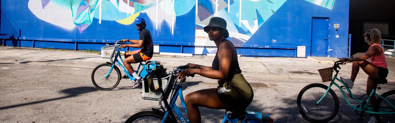 Tampa Bay locals gaze at massive wall art at the bimonthly Mural Cycle St. Pete street art tour, a new business created by Monica DeChaine to help get people out exercising and enjoying street art.