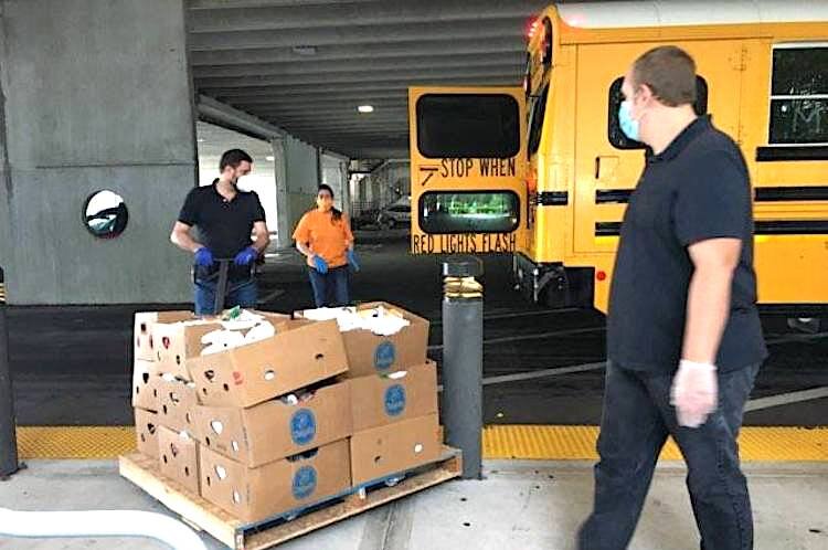 Volunteers load boxes of food onto Pinellas County school buses for distribution to families in need.