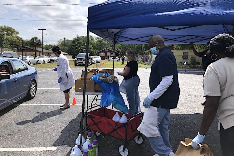 USF College of Nursing staff and volunteers from the Abundant Life Church provide car-side pickup following social distancing guidelines. Approximately 50 families attended the event to receive essential groceries and household items.