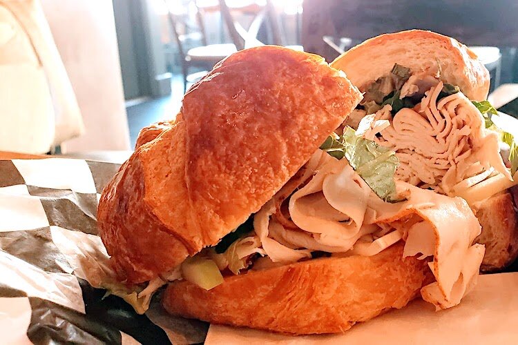 Ample sandwiches, like this one loaded with turkey, apple, and brie on a croissant, are on the menu at Grindhouse.