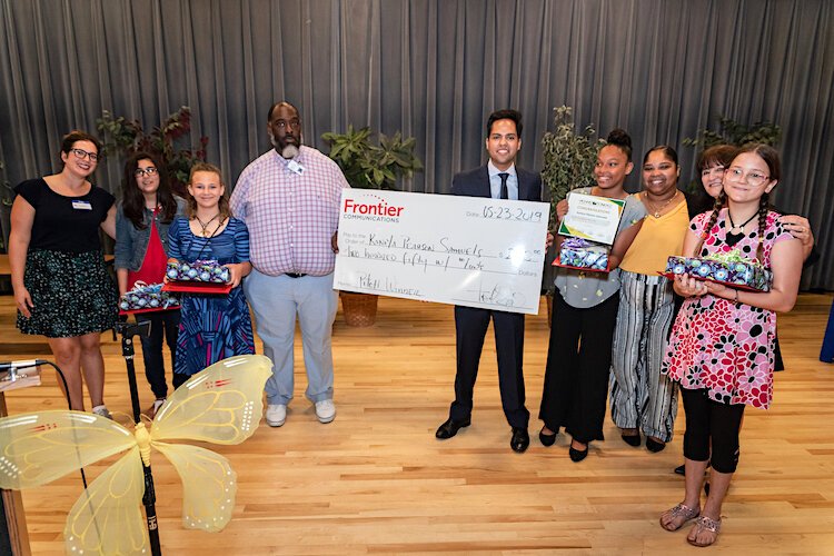 Tony Selvaggio holds the check from Frontier Communications for the Dowdell Middle School student who won the business pitch competition.