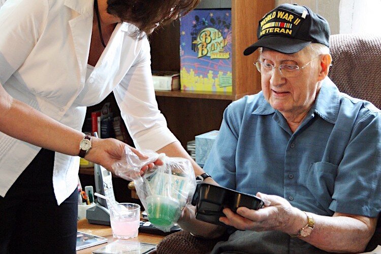 A Meals on Wheels volunteer serves a World War II veteran.
