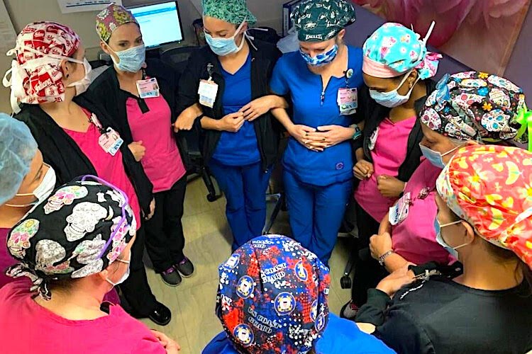 A team of caregivers forms a prayer circle.