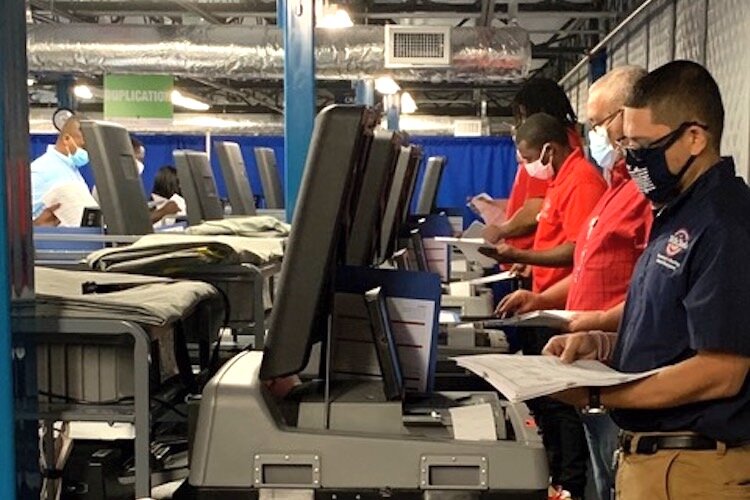 A team of workers checks the accuracy of electronic vote counting machines.