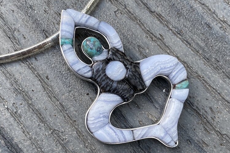 Swan Dive, sterling silver pendant with 18 pieces of blue lace agate, chrysocolla, and dinosaur bone.