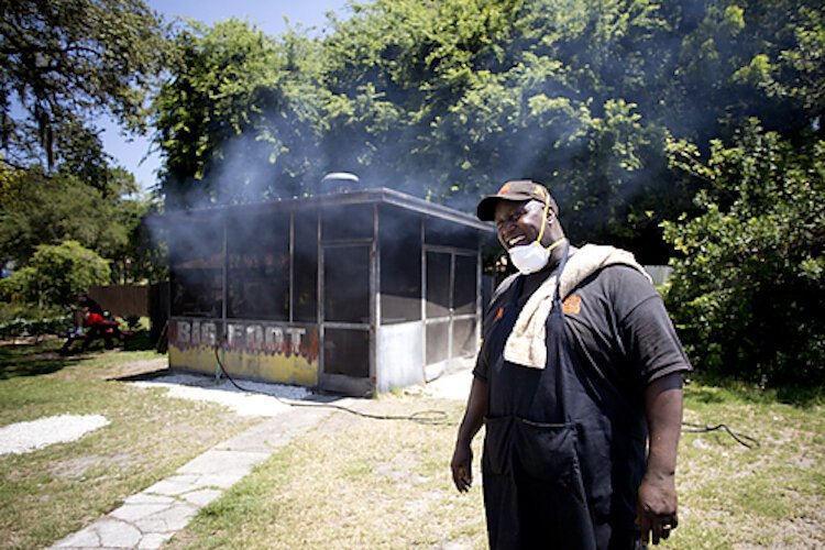 Eric Davis steps from the smokehouse at Eli's Bar-B-Que wearing an apron and a towel draped over his shoulder and a savory cloud follows.