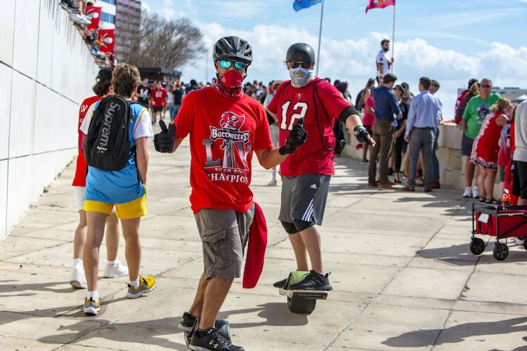 Masked skate boarders buzz among thousands of Tampa Bay Bucs fans on The Tampa Riverwalk.