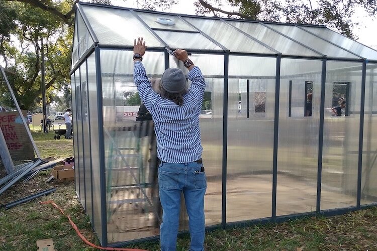 A community volunteer working on a small greenhouse.
